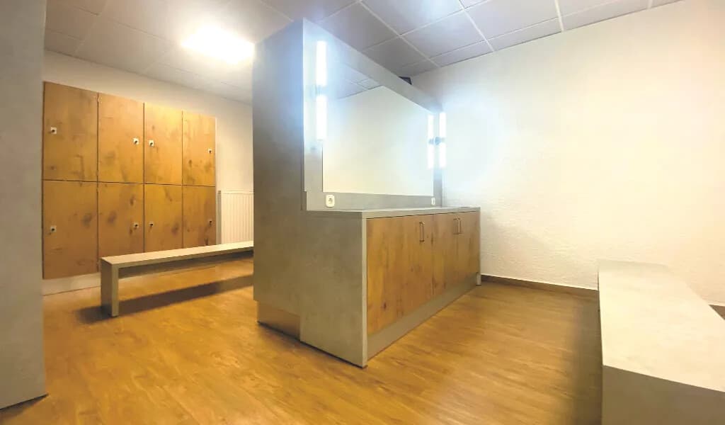 Umkleide im Studio Bürstadt mit Holzspinden, Bank und beleuchtetem Spiegel